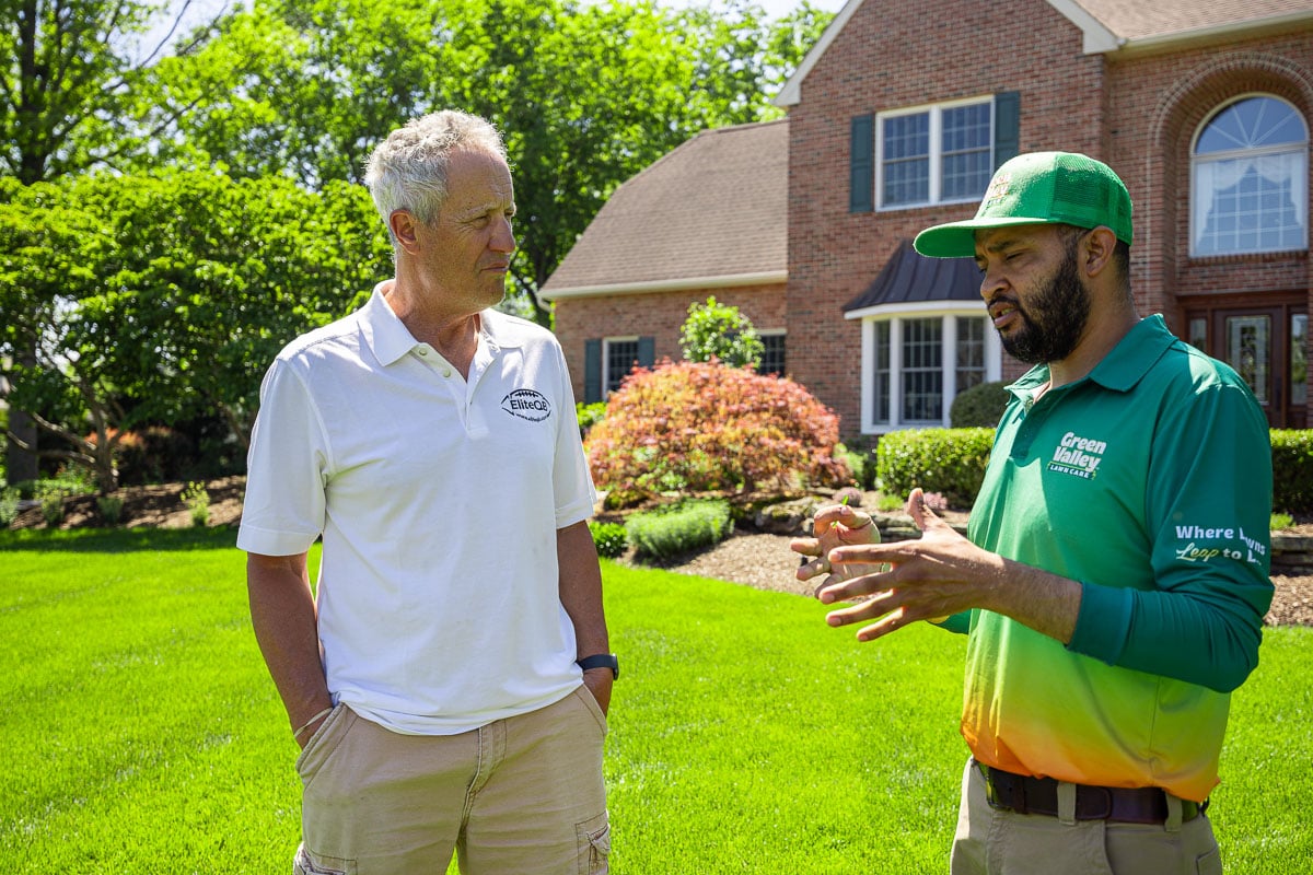customer homeowner with lawn care technician - green valley lawn care